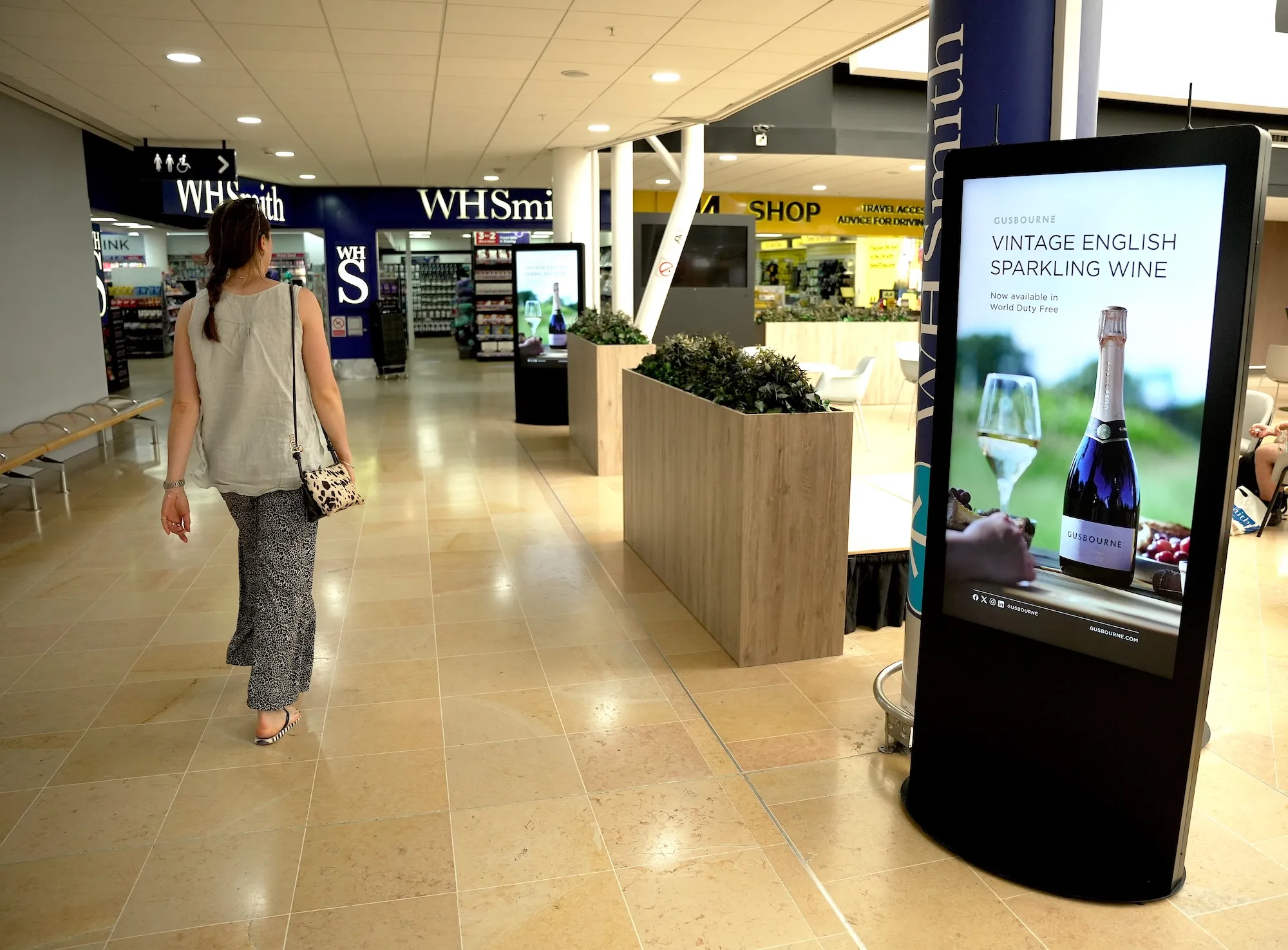 A woman walking past a large digital advertising screen at the LeShuttle terminal